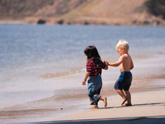 Little ones running on the beach hand in hand.